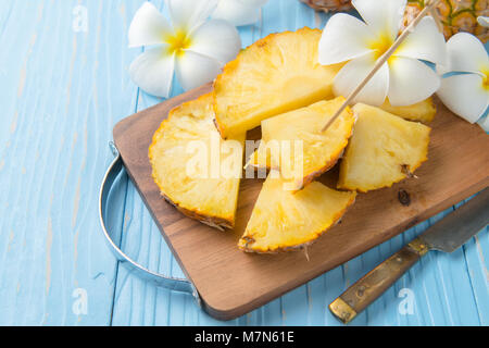 Fresco di ananas a fette sul blocco di legno e legno blu sfondo, frutta estiva concept Foto Stock