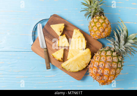 Fresco di ananas a fette sul blocco di legno e legno blu sfondo, frutta estiva concept Foto Stock