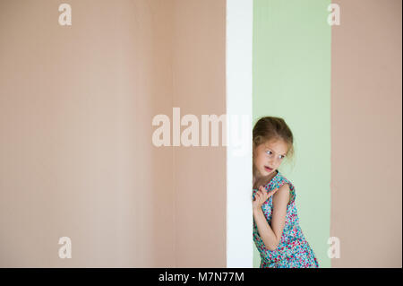Piccola e bella ragazza si nascose dietro l'angolo nella nuova camera Foto Stock