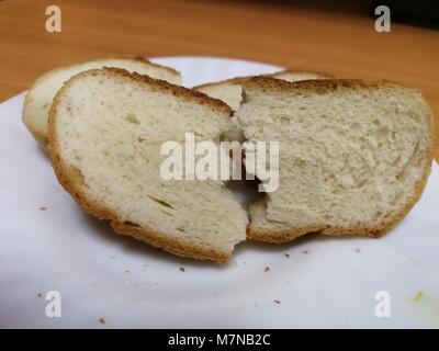 Asciugare i pezzi tagliati a fette della focaccia giacente su un piattino bianco Foto Stock