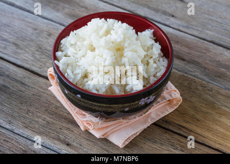 Riso in tazza su sfondo di legno Foto Stock