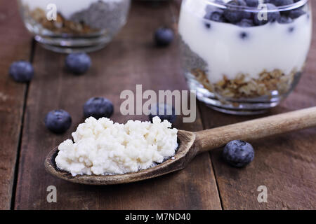 Il Kefir grani in cucchiaio di legno nella parte anteriore di tazze di Kefir Yogurt Parfaits. Il Kefir è uno dei top salute alimenti disponibili fornendo potenti probiotici. Foto Stock