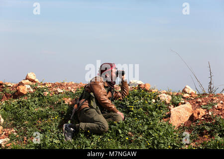 Afrin. Undicesimo Mar, 2018. Un bagno turco-backed libero esercito siriano fighter osserva attraverso il campo bicchieri in Afrin, Siria settentrionale, il 11 marzo 2018. Il bagno turco e le forze alleate ribelli Siriani sono stati 4 km a nord-est del curdo-Afrin controllata della città nel nord della Siria, un gruppo di monitor riportati su Sabato. Credito: Xinhua/Alamy Live News Foto Stock