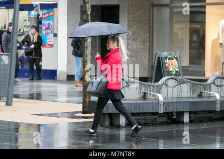 Southport, Merseyside. Xii Marzo 2018. Regno Unito Meteo. Inizio mattino acquazzoni pioggia verso il basso gli acquirenti come loro riparo sotto i loro ombrelli a Southport nel Merseyside. Showery focolai di pioggia continuerà questo pomeriggio, alcuni dei quali sarà lungo. Un paio di raffiche pesanti con un rischio di tuoni sono possibili più tardi nel pomeriggio. Credito: Cernan Elias/Alamy Live News Foto Stock