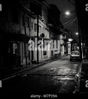 Holguin, Cuba - Agosto 31, 2017: una stretta fiocamente illuminate street è vacante dopo un acquazzone. Foto Stock