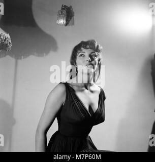 Joan Collins, attrice, 22 anni, raffigurata vestita di nero Seta abito da cocktail, al suo appartamento in Marylebone, London, 10 febbraio 1954. Foto-chiamata dopo dieci mesi di soggiorno a Hollywood. Foto Stock