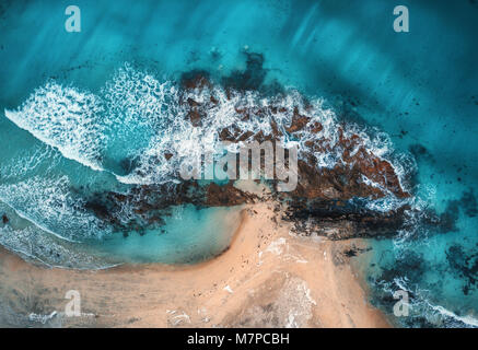 Vista aerea di onde, rocce e mare trasparente. Estate seascape con vista oceano, spiaggia sabbiosa, onde bellissime, scogliere, acqua blu al tramonto. Vista superiore da Foto Stock