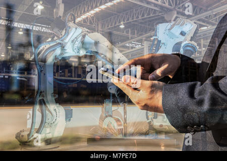 Imprenditore è usato Smart Phone Control automatizza wireless robot di saldatura. È industrial4.0 concetto con doppia esposizione Foto Stock