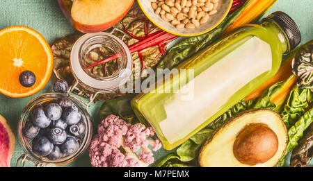 Frullato verde bevanda in bottiglia con vari piatti vegan sani ingredienti: orange,mirtilli,l'avocado, vista dall'alto. Detox, dieta e pulire mangiare, vegetari Foto Stock