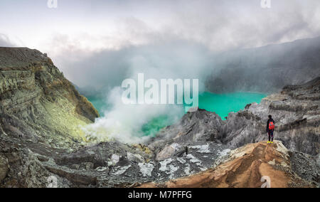 Vista panoramica di zolfo ardente fiamme del cratere Ijen e il verde smeraldo laghetto vulcanico oltre che su i fumi Foto Stock