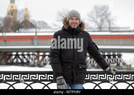 Uomo maturo in abbigliamento invernale contro San la fortezza di Pietro e Paolo a San Pietroburgo, Russia Foto Stock