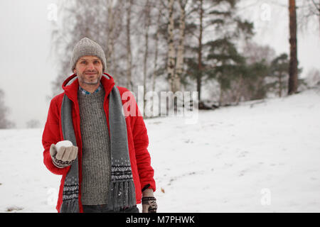 Uomo maturo con palla di neve durante la lotta con le palle di neve Foto Stock