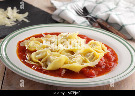 Ravioli con pomodoro e formaggio parmigiano su un tavolo rustico Foto Stock