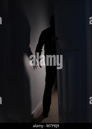 Ombra di un uomo con il braccio esterno di entrare in una stanza buia Foto Stock