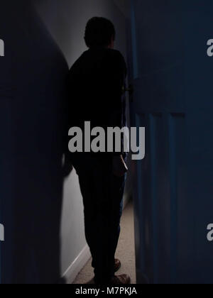 Creepy uomo di mezza età entrando in una stanza buia cercando come un ladro Foto Stock