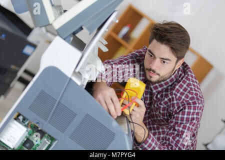 Giovane tecnico utilizzando il multimetro Foto Stock