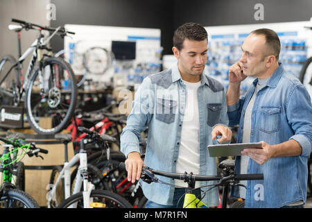 Guy positivo noleggio di bici a noleggio store Foto Stock