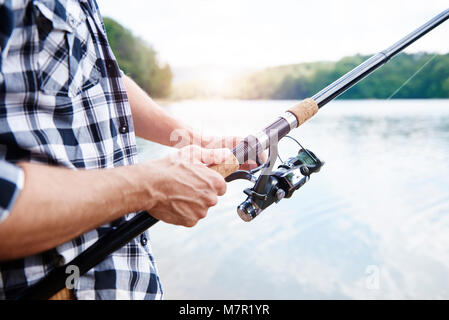 Mano umana tenendo la canna da pesca Foto Stock