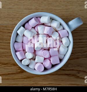 Vista aerea del mini marshmallows in tazza bianca sulla superficie di quercia Foto Stock