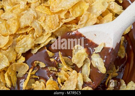 La miscelazione di fiocchi di mais e cioccolato fuso con il cucchiaio di legno Foto Stock