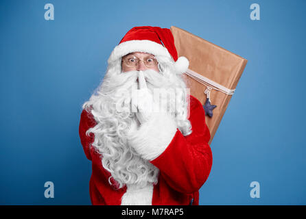 Babbo Natale di contenimento presenta alle sue spalle Foto Stock