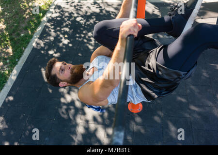 Uomo Forte facendo appendere solleva la gamba per muscoli addominali Foto Stock