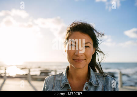 Ritratto di una donna in piedi vicino al litorale. Donna su una vacanza in piedi vicino al mare. Foto Stock