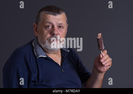 Bel ritratto di un barbuto senior con nibbled di gelati su un bastone Foto Stock