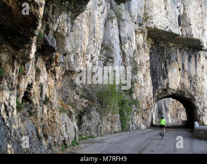 Un ciclista si avvicina un tunnel sulla strada formando il Cirque de Combe Laval nel Vercors regione delle Alpi francesi Foto Stock