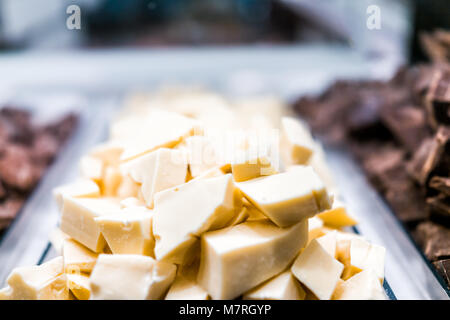 Macro closeup di pelo di molti il cioccolato bianco pezzi pezzi sul vassoio di vetro del display nel negozio di caramelle chocolatier shop Foto Stock