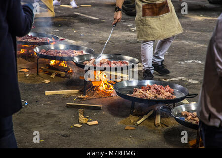 VALENCIA, Spagna - 3/12/2018: fila di paella pentole con la carne per la cottura su un fuoco aperto per alimentare l'equipaggio che sta costruendo il ninots per Fallas Foto Stock