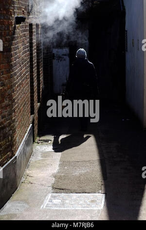 La figura camminando in un buio misty vicolo. Foto Stock