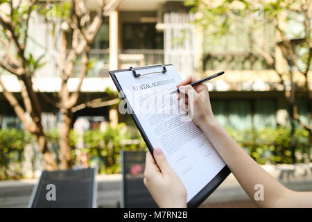 Close up donna mani firma il contratto di noleggio giornata soleggiata in condominio Foto Stock