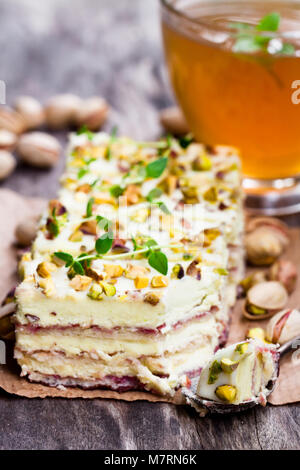 Fette di torta a strati con pistacchio e un bicchiere di verde il tè alle erbe Foto Stock