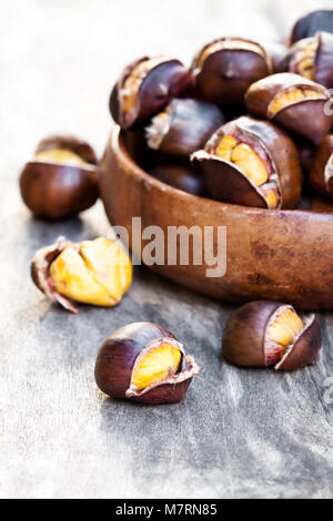 Arrosto di castagne nella ciotola di legno Foto Stock