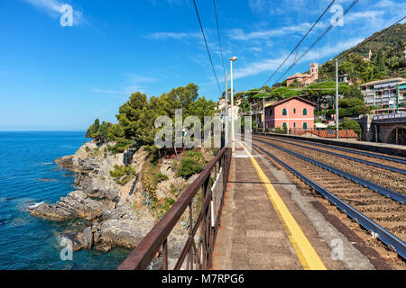 Piattaforma sulla piccola stazione locale e i binari della ferrovia lungo la bellissima costa mediterranea in Liguria, Italia. Foto Stock