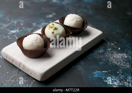 Cioccolatini fatti a mano con ripieno di formaggio su uno sfondo scuro. bianco latte al cioccolato. chiusa fino Foto Stock