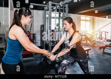 Donna cavo facendo volare esercizio in posizione di affondo nel moderno centro fitness con l'aiuto del suo personal trainer. Foto Stock