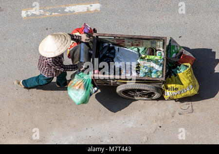A Saigon, Vietnam, DIC 17 2017, la raccolta di rifiuti riciclabili per le strade della città di Ho Chi Minh. Donna vietnamita spingendo un carrello pieno di borse, Saigon Foto Stock