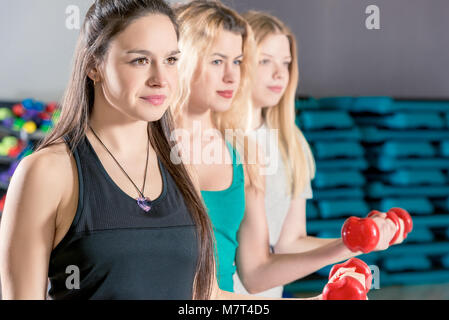 Close-up verticale di tre ragazze in formazione con manubri Foto Stock