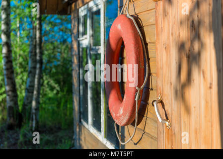 Vecchio salvagente close-up su una parete in legno di una casa rurale vicino a un lago Foto Stock