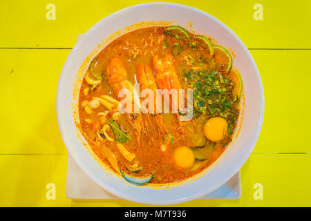 Al di sopra di vista della zuppa di gamberetti in bianco ciotola sul tavolo giallo in Ao Nang Foto Stock