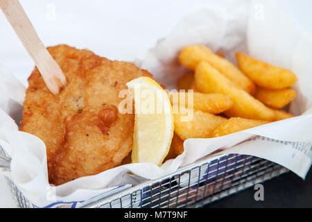 Pesce e patatine, con una forcella di chip in un cestello di metallo. Foto Stock