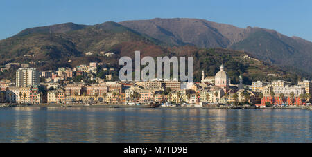 Pegli tipico villaggio in Genova Liguria vista dal mare, colorate case strette, palme e grande chiesa riflettente nel mare Mediterraneo. Mounta Foto Stock