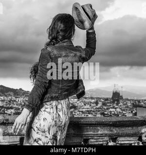 Serata perfetta con vista mozzafiato. Visto da dietro il turista alla moda donna in abiti lunghi e cappello di paglia nella parte anteriore del paesaggio urbano di Barcellona, Spagna h Foto Stock