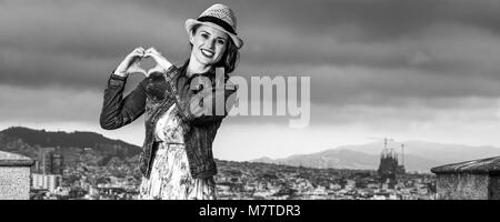 Serata perfetta con vista mozzafiato. Sorridendo viaggiatore eleganti donna in abiti lunghi e cappello di paglia nella parte anteriore del paesaggio urbano di Barcellona, Spagna mostra Foto Stock