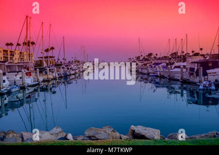 Cielo di tramonto su porto con barche, acqua blu, arancione, rosso, rosa e viola il cielo. Foto Stock