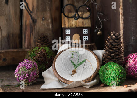 Cartolina a molla con la croce cucita snowdrop sullo sfondo di legno. Tonica. Foto Stock
