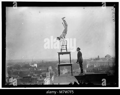 J. Reynolds è raffigurato eseguendo atti acrobatici e bilanciati su un'alta cornice sopra la 9th Street a Washington, D.C. l'immagine cattura la natura audace dello spettacolo di strada e dell'intrattenimento pubblico. Foto Stock