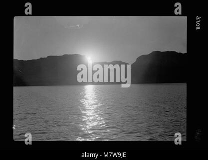 Una fotografia drammatica del sole che tramonta dietro la ripida costa occidentale del Mar morto, catturando la bellezza naturale unica e le caratteristiche geologiche della regione. Foto Stock